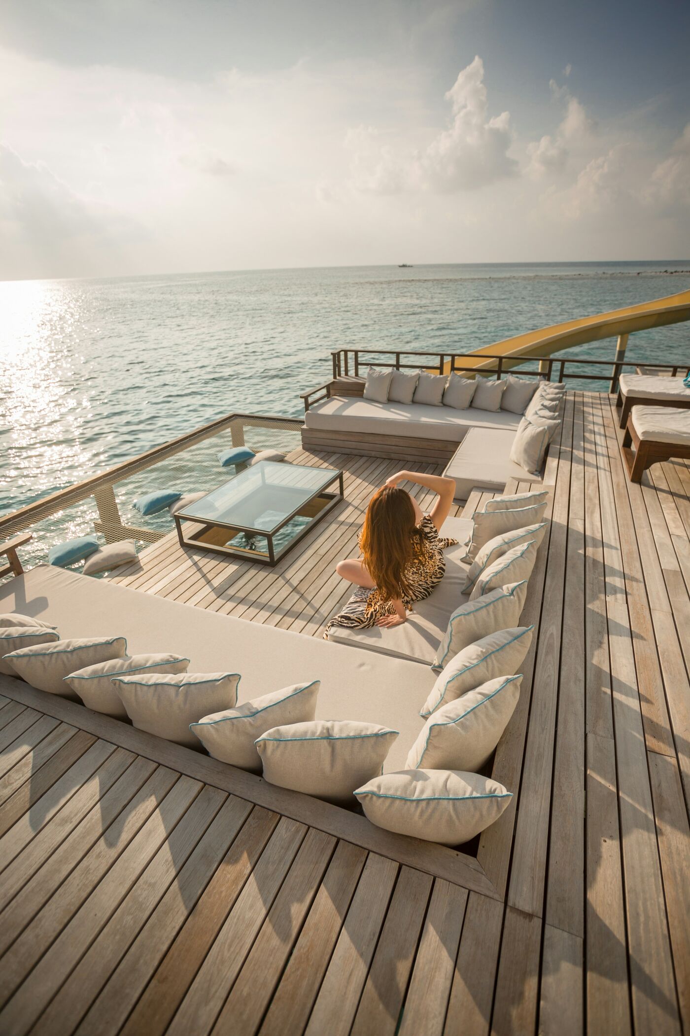 A guest alone on the sun deck, cushions and a low table laid out on teak