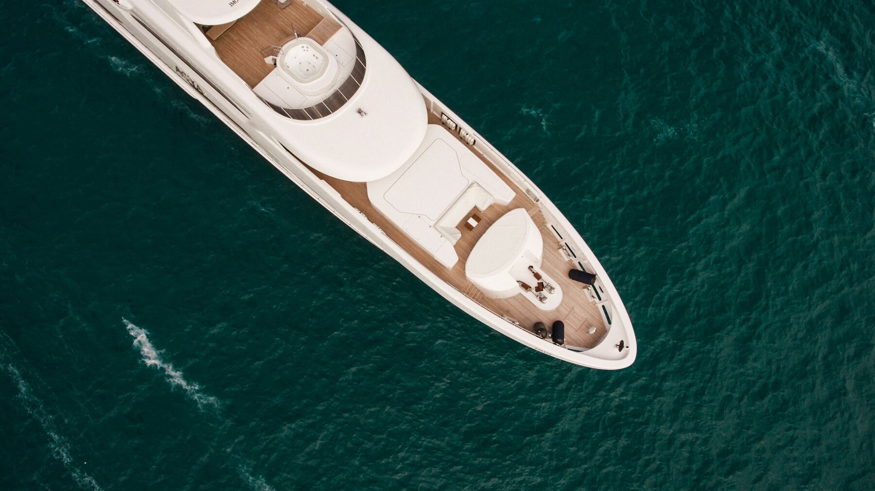 Azure Pearl seen from above, her teak foredeck and sun pads laid out on dark water