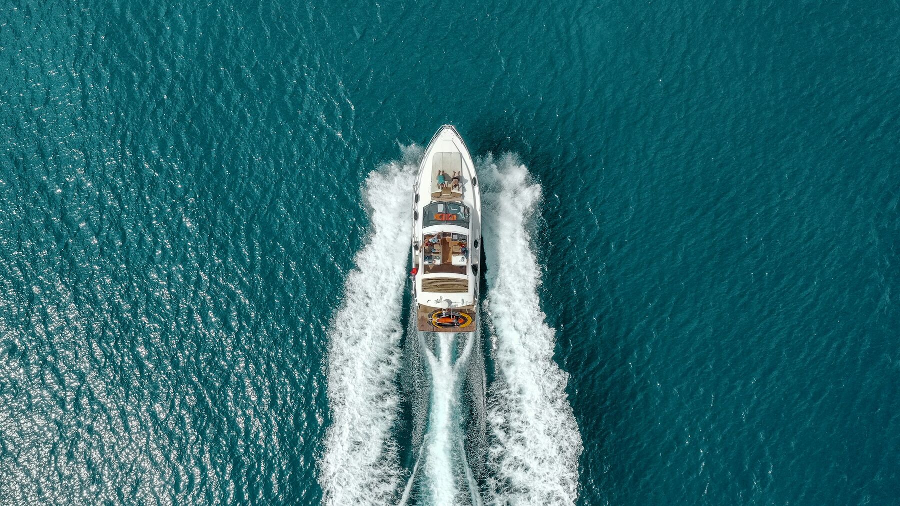 Desert Wind under way, throwing a long white wake across open blue water